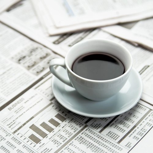 A cup of coffee on a table full of newspapers on Chicago, IL