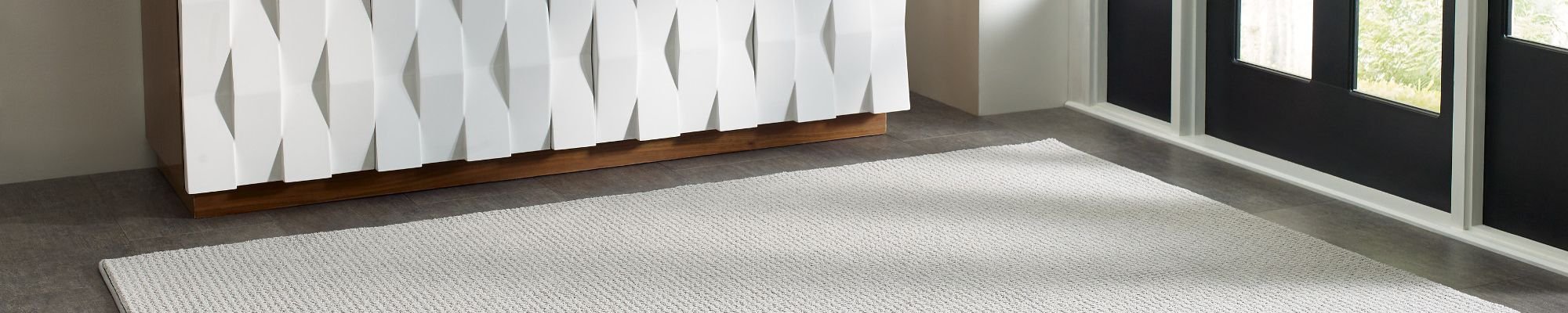 White cabinet on entrance area and a white rug in front of a black door in Chicago, IL